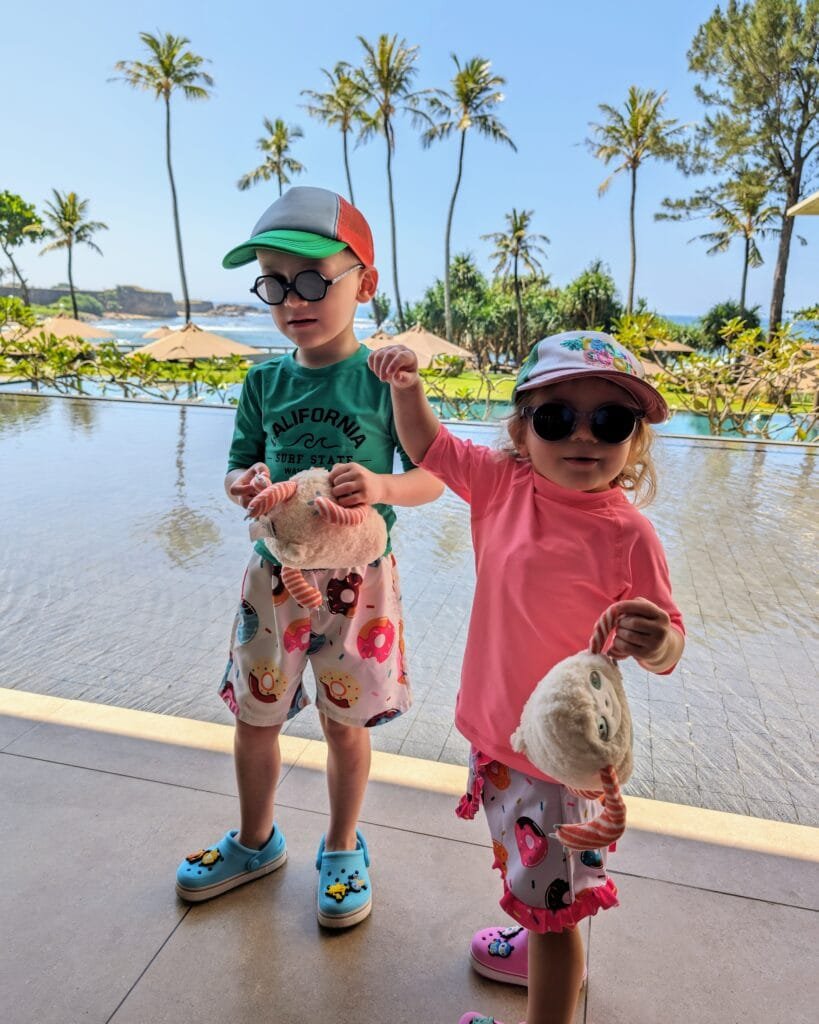 Les enfants en maillot de bain, t-shirt UV, crocs, casquette et lunettes de soleil