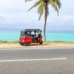 Tuk-tuk rouge de location garé au bord d'une route côtière du Sri Lanka, face à la mer